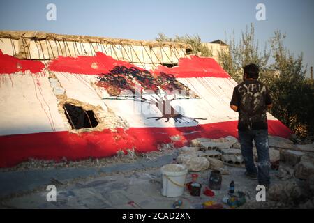 Idlib, Syrien. August 2020. Ein Syrer sah am 6. August 2020 in der Stadt Bennach östlich von Idlib eine libanesische Flagge an den Wänden malen, um die Syrer mit dem libanesischen Volk zu solidarisieren, nachdem der Hafen von Beirut gestern einer gewaltigen Explosion ausgesetzt war, bei der mehr als 100 und 4000 Verletzte getötet wurden. (Foto von Ali Haj Suleiman/INA Photo Agency/Sipa USA) Quelle: SIPA USA/Alamy Live News Stockfoto