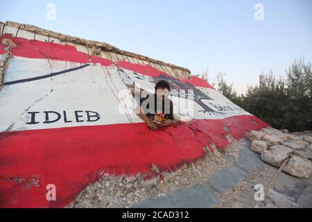 Idlib, Syrien. August 2020. Ein Syrer sah am 6. August 2020 in der Stadt Bennach östlich von Idlib eine libanesische Flagge an den Wänden malen, um die Syrer mit dem libanesischen Volk zu solidarisieren, nachdem der Hafen von Beirut gestern einer gewaltigen Explosion ausgesetzt war, bei der mehr als 100 und 4000 Verletzte getötet wurden. (Foto von Ali Haj Suleiman/INA Photo Agency/Sipa USA) Quelle: SIPA USA/Alamy Live News Stockfoto