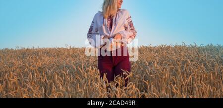 Ukrainisches Mädchen in weißen ethnischen Stickereien Hemd. Mädchen im gestickten Hemd und einem Kranz auf dem Kopf auf Weizenfeld. Ukrainische nationale Kleidung. Stockfoto