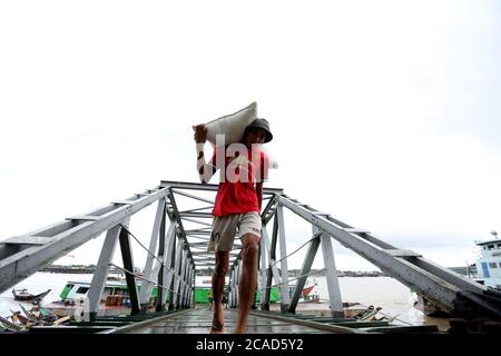 Yangon, Myanmar. August 2020. Ein Arbeiter trägt Reisbeutel an einem Steg in Yangon, Myanmar, 6. August 2020. Myanmar exportierte über 2.25 Millionen Tonnen Reis und gebrochenen Reis ab Juli 17 in diesem Geschäftsjahr (GJ) 2019-2020, nach einer Pressemitteilung der Myanmar Rice Federation am Mittwoch. Quelle: U Aung/Xinhua/Alamy Live News Stockfoto