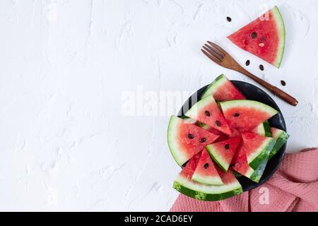 Geschnittene frische Wassermelone in schwarzer Schale Draufsicht auf weißem Tisch Stockfoto