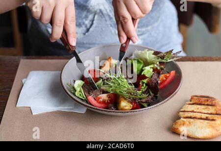 Frau essen gesunden Salat mit Rindfleisch, Gemüse, Kräuter im Café Stockfoto