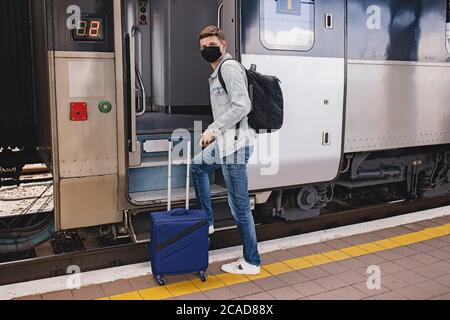 Mann trägt Schutzgesicht maskgoing, um den Intercity-Zug zu betreten. Stockfoto