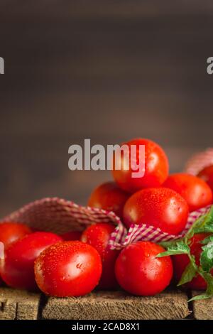 Natürliches Produktkonzept. Frische lange Pflaumentomaten mit rot kariertem Küchentuch. Leerzeichen für Text Stockfoto