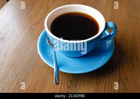 Blaue Tasse mit schwarzem Kaffee auf dem Holztisch Stockfoto