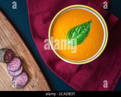 Eine Schüssel mit Tomatensuppe und Salami. Stockfoto