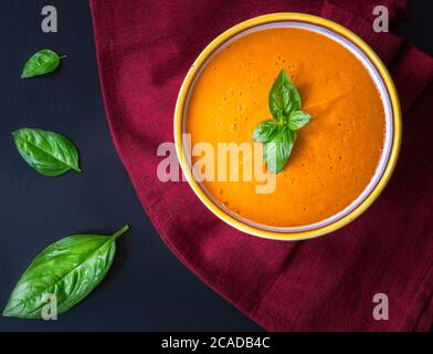 Eine Schüssel Tomatensuppe mit Basilikumblättern. Stockfoto