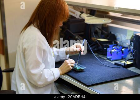Frau Löten einer Leiterplatte in ihrem Tech-Büro.Nahaufnahme einer Ingenieurin mittleren Alters mit Lot in ihrem Büro. Testen und Fixieren einer Leiterplatte. Stockfoto