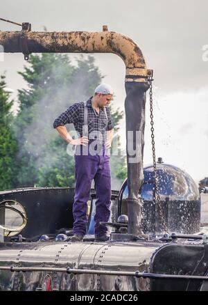 Dampflokomotive Crew Feuerwehrmann steht auf alten Dampflokomotive, wie es auf Wasser in den Nebengleisen in Severn Valley Heritage Bahnhof, Großbritannien nimmt. Stockfoto