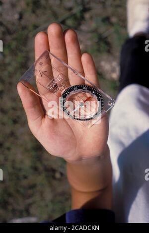 Bandera, Texas, USA, um 1991: Mädchen der vierten Klasse verwendet Kompass und Karte, um den Standort während einer Campingtour mit Übernachtung zu schätzen. ©Bob Daemmrich Stockfoto