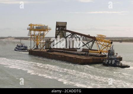 Port Aransas, Texas, USA, 15. Januar 2006: Ein Binnenschiff mit einer Flachwasserbohrplattform und einem Kran wird von einem Schlepper aus der Aransas Bay gezogen. ©Bob Daemmrich Stockfoto