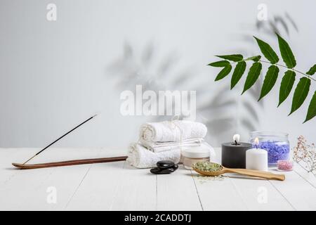 Schöne Spa-Komposition auf Massageliege im Wellness-Center, Copyspace. Zubehör für entspannende Behandlungen und Körperpflege. Handtücher, Öle, Serum, Meersalze und Peelings. Dekorative Kerzen. Stockfoto