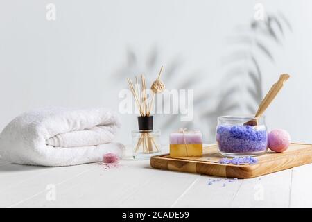 Schöne Spa-Komposition auf Massageliege im Wellness-Center, Copyspace. Zubehör für entspannende Behandlungen und Körperpflege. Handtücher, Öle, Serum, Meersalze und Peelings. Dekorative Kerzen. Stockfoto