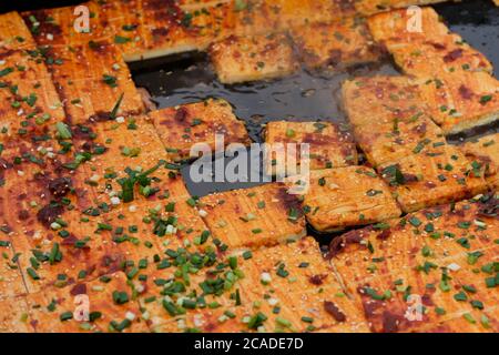 Nahaufnahme Stinky Tofu auf Bratpfanne mit grüner Zwiebel und Chili. Ein traditioneller chinesischer fermentierter Snack. Stockfoto