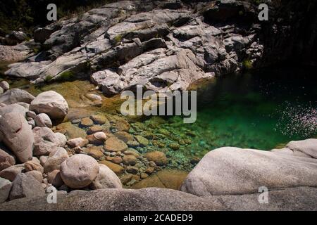 Kristallklares, türkisgrünes Wasser auf dem Bergsee, das auf dem Boden runde Felsen zeigt. Stockfoto