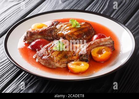 Gourmet-Rezept für gegrilltes Schweinekotelett mit Pflaumen und Obstsauce close-up in einem Teller auf dem Tisch. Horizontal Stockfoto