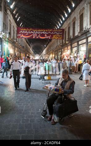 Syrer, die durch den geschäftigen und überfüllten Al Hamidiyah Markt, einen typischen nahöstlichen Souk in der Altstadt von Damaskus, Syrien, wandern. Stockfoto