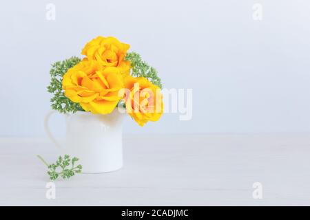 Romantisches Bouquet von gelben Rosen in einem Glas auf weißem Holzhintergrund. Für Text platzieren. Stockfoto