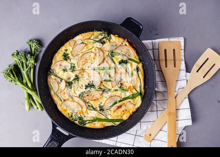 Gebackenes Ei frittata mit Käse und Brokkolini auf grauem Tisch Stockfoto