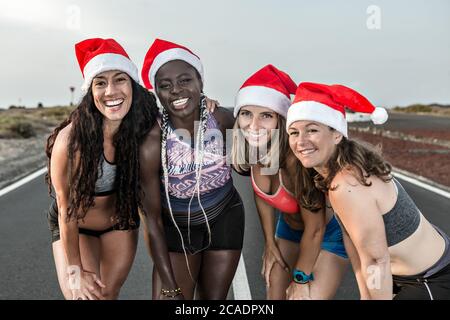 4 Läuferinnen in der Gruppe lächeln mit weihnachtsmütze Stockfoto