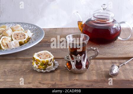Türkischer Tee in einer traditionellen Tasse auf einem Holztisch. Teetrinken mit orientalischen Süßigkeiten und einem duftenden Getränk. Stockfoto