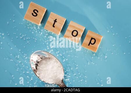 WORTSTOPP aus Holzbuchstaben und verkohlenem Zucker auf blauem Hintergrund. Stockfoto