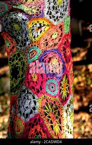 Park in Eureka, Springs hat Baumstämme mit alten gehäkelten afghanen Recycling sie geschmückt. Dieses Muster hat Blumen in mehreren Farben. Stockfoto