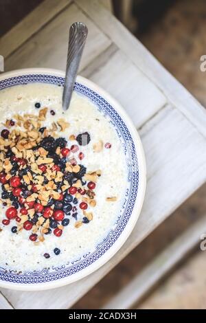 Schale mit blauem Nationalmuster mit Quark und Joghurt-Smoothie mit Chia, Himbeeren, roten Johannisbeeren, Heidelbeeren, Brombeeren, Walnüssen auf einem Stockfoto