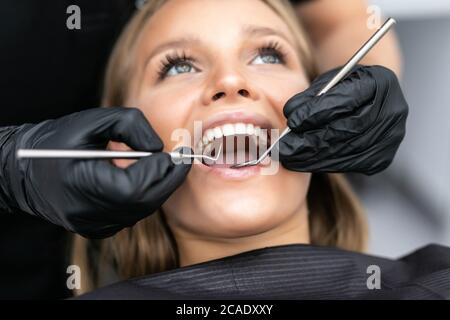 Die Frau kam zum Zahnarzt. Sie sitzt in den zahnmedizinischen Stuhl. Der Zahnarzt beugte sich über sie. Gerne Patient und Zahnarzt Konzept. Stockfoto