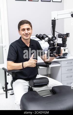 Ein männlicher Zahnarzt steht mit einem Mikroskop Stockfoto