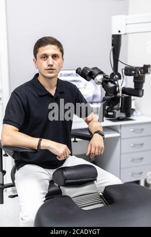 Ein männlicher Zahnarzt steht mit einem Mikroskop Stockfoto