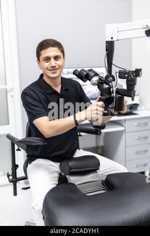 Ein männlicher Zahnarzt steht mit einem Mikroskop Stockfoto