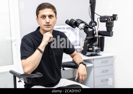 Ein männlicher Zahnarzt steht mit einem Mikroskop Stockfoto