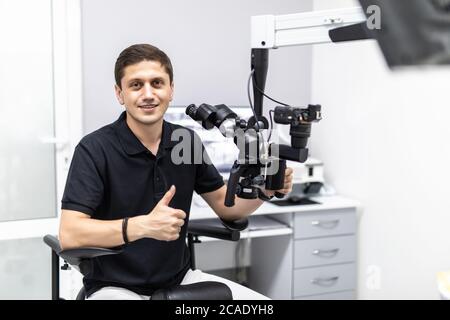 Ein männlicher Zahnarzt steht mit einem Mikroskop Stockfoto