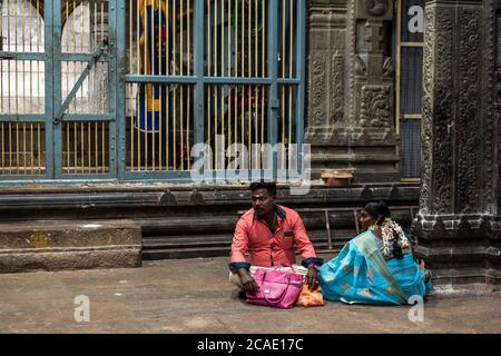 Kumbakonam, Tamil Nadu, Indien - Februar 2020: Indische Pilger sitzen auf dem Steinboden einer beleuchteten Halle im alten Hindu-Tempel von SW Stockfoto