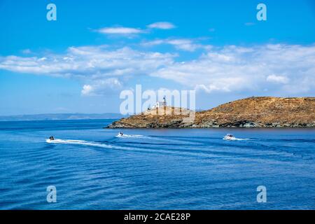 Aufblasbare Schnellboote, die im mittelmeer kreuzen. Leuchtturm auf einem Kap, blauer wolkiger Himmel und Meereswasser Hintergrund, sonniger Tag. Griechenland, Kea Tzia isl Stockfoto