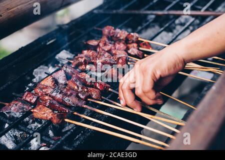 Hand Grillen Schweineleber in Bambus Spieße über heißen Holzkohleffeuer. Selektiver Fokus. Stockfoto