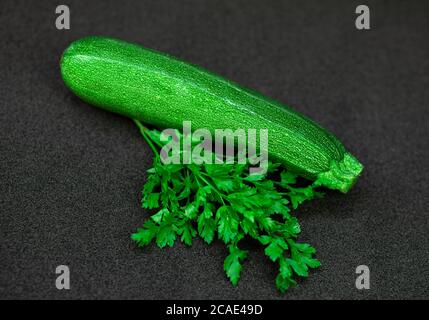 Zucchini und Petersilie auf dunklem Grund Stockfoto