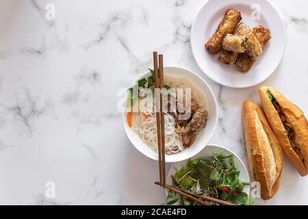High-Angle-Aufnahme von verschiedenen asiatischen Gerichten mit Essstäbchen auf Eine Marmoroberfläche Stockfoto