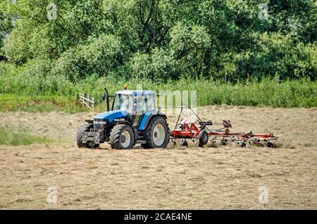 Wilsum, Niederlande, 21. Juli 2020: Landwirtschaftliche Maschine bei der Arbeit in einem Feld der Heutrocknung Stockfoto