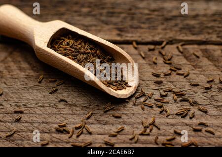 Nahaufnahme der Kümmel Samen in einem Holzlöffel auf Eine hölzerne Oberfläche Stockfoto