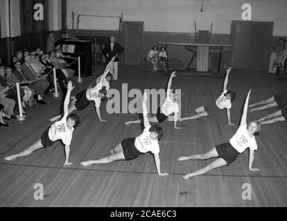 Um 1940er Jahre, historische, weibliche Gymnasiasten, die eine künstlerische gymnastische Darstellung vor dem Betrachten der Besucher, USA. Stockfoto