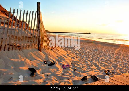 Sommerzeit auf Cape Cod, Massachusetts. Lange Schatten und warmes Sonnenlicht am späten Nachmittag beleuchten diese Strandszene von Cape Cod mit verlassenen Schuhen. Stockfoto