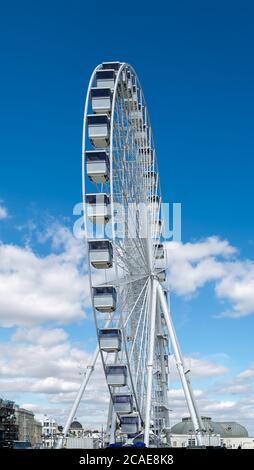 An der Strandpromenade von Worthing bietet ein Riesenrad einen malerischen Blick auf die Küste, bei schönem Wetter gibt es Wolken, die auf einen heißen Tag hindeuten. Stockfoto