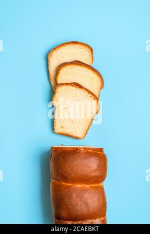 Geschnittenes Hokkaido-Milchbrot mit Sauerteig, natürliche Gärung, isoliert auf blauem Hintergrund. Blick von oben auf hausgemachtes Brot. Japanisches Rezept. Stockfoto