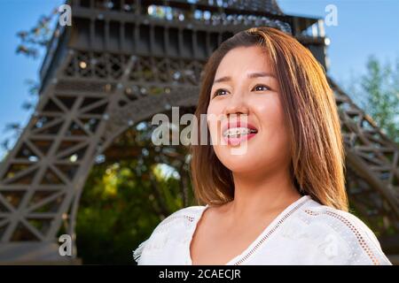 Ein Mädchen mit asiatischem Auftritt in einem weißen T-Shirt sieht zur Seite und lächelt auf ihren Zähnen Zahnspangen Stockfoto