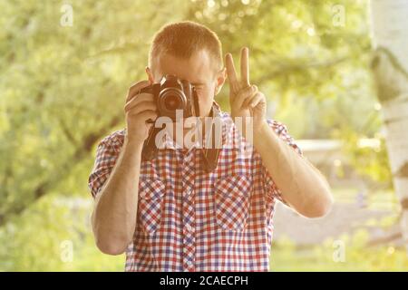 Der Fotograf fotografiert vor dem Hintergrund von Grün. Vorderansicht. Siegeshand Stockfoto