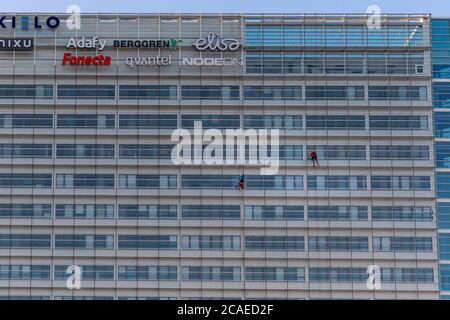 Das Waschen der Fenster eines Wolkenkratzers ist immer ein großes Projekt. Kletterer waschen Glasfassade eines hohen Bürogebäudes in Jyväskylä, Mittelfinnland. Stockfoto