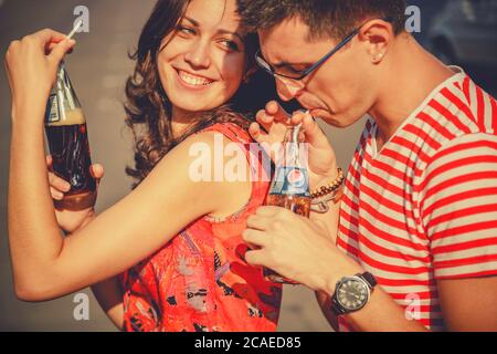 ODESSA, UKRAINE - 15. OKTOBER 2014: Nahaufnahme von schönen jungen lächelnden Paar in der Liebe, Umarmung im Freien trinken kalt Pepsi aus Glasflaschen mit Stockfoto