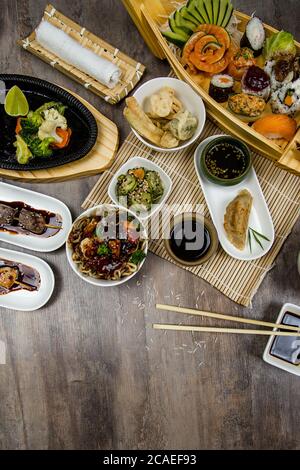 Vertikale High-Angle-Aufnahme von verschiedenen asiatischen Gerichten auf einem Holztisch Stockfoto